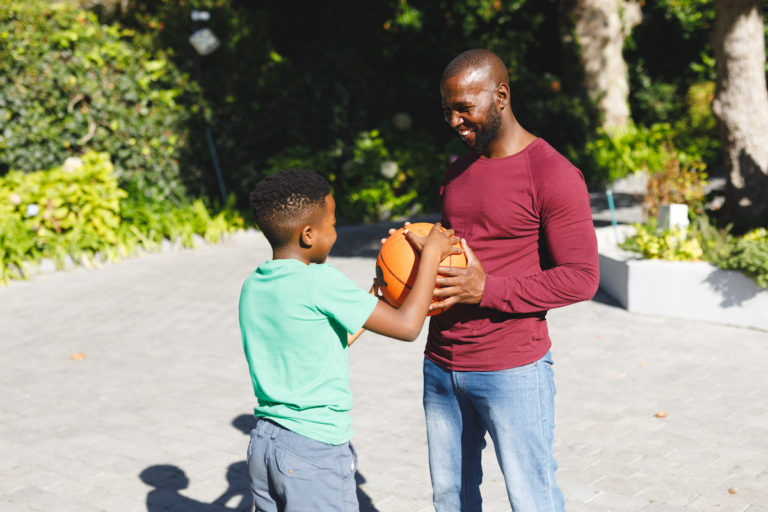Father and son smiling and holding a basketball