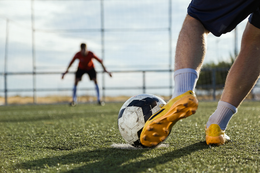 Soccer player kicking a ball. A sports injury clinic is standing by for injuries.